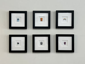 A gallery wall featuring six hyper-realistic miniature paintings by artist Karen Libecap. This tiny art collection showcases detailed wildlife and nature subjects, highlighting the exclusive small-scale artwork available through her monthly art subscription box. The collection features realistic animals and everyday objects in a miniature format, representing the unique gallery-quality pieces included in her art subscription service.